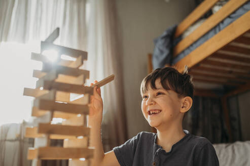 Happy boy playing block removal game at home - ANAF02841