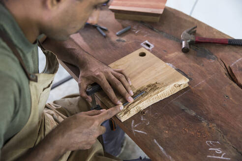 Schreiner beim Schnitzen von Holz mit einem Meißel in der Werkstatt - IKF01769