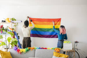 Junge nicht-binäre Person und Freund dekorieren Haus für Schwulenstolz-Party - JCCMF11639