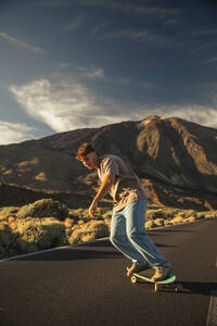 Unbeschwerter Mann beim Skateboarden auf der Bergstraße vor dem Teide - ACPF01574