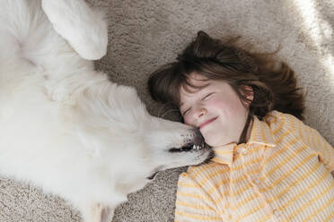 Nettes Mädchen und Hund auf Teppich liegend zu Hause - ELMF00194