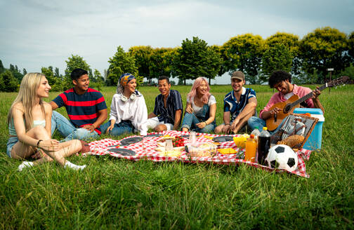 Eine Gruppe multiethnischer Jugendlicher verbringt ihre Zeit bei einem Picknick im Park. Konzept über die Generation Z, Lebensstil und Freundschaft - DMDF11448