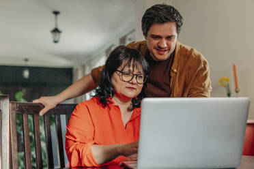 Mann hilft Mutter bei der Benutzung des Laptops zu Hause - VSNF01855