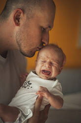 Vater küsst weinenden kleinen Jungen zu Hause - ALKF01175