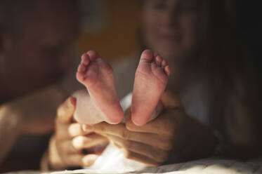 Mother holding baby boy's legs at home - ALKF01177