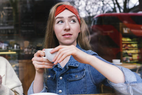 Young woman holding coffee cup in cafe - ASGF04977
