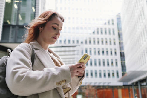 Frau benutzt Smartphone vor einem Gebäude - ASGF04984