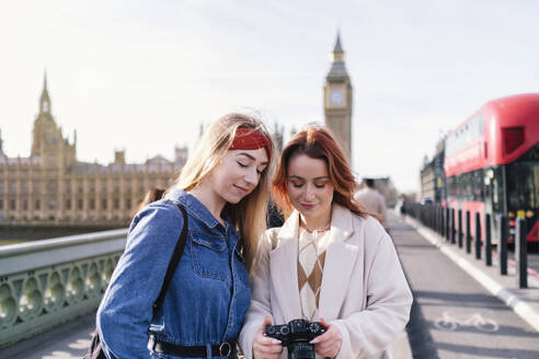 Smiling friends standing with camera in city of London, England - ASGF05005