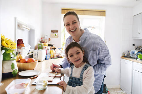 Glückliche Mutter und Tochter bereiten Essen in der Küche zu Hause vor - ASGF05011