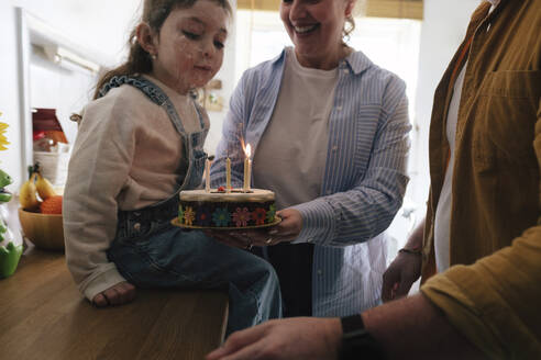 Glückliche Eltern feiern den Geburtstag ihrer Tochter mit Kuchen zu Hause - ASGF05023
