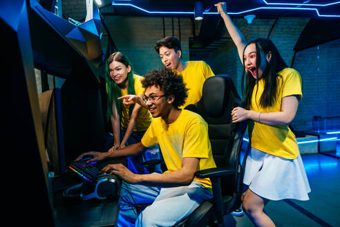 Multiethnic group of young friends playing videogames - Team of professional esport gamers playing in competitive video games on a cyber games tournament - DMDF11648