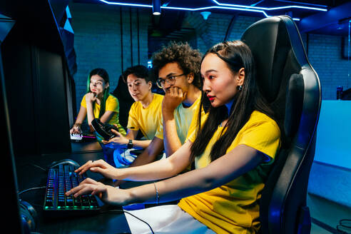 Multiethnische Gruppe junger Freunde, die Videospiele spielen - Team professioneller esport-Spieler, die in wettbewerbsfähigen Videospielen an einem Cyber-Games-Turnier teilnehmen - DMDF11666