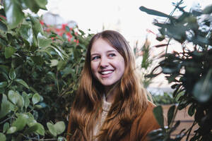 Lächelnde junge Frau inmitten von Grünpflanzen - AMWF02144