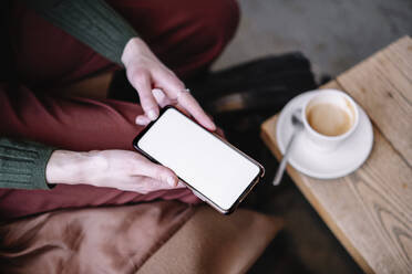 Geschäftsfrau hält Smartphone im Café - AMWF02174