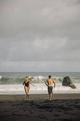 Carefree young couple running towards sea at beach - ACPF01584