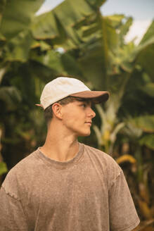 Boy with a cap in front of some banana trees looking to the side. Tenerife, Canary Islands, Spain - ACPF01597