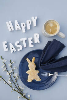 Happy Easter phrase, blackthorn twigs, mug of coffee and bunny shaped cake - GISF01065
