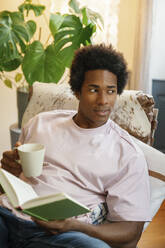 young man drinking coffee and reading a book - FLMZF00047