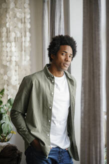 portrait of handsome young man standing in living room - FLMZF00069