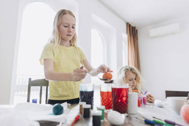 Two sisters are coloring and decorating eggs for Easter - SIF01080