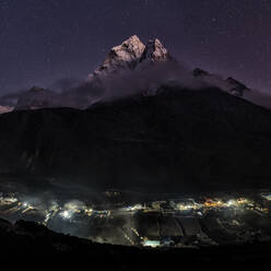 Nepal, Khumbu, Dingboche, Ama Dablam looming over illuminated village at night - ALRF02122