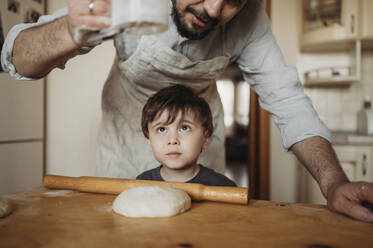 Father and son kneading dough in kitchen at home - ANAF02850