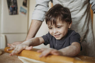 Smiling son helping father in kitchen at home - ANAF02859