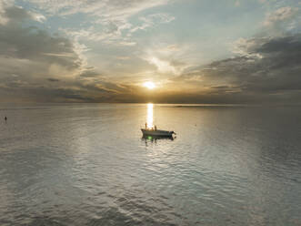 Luftaufnahme von Menschen beim Fischen auf einem Boot im ruhigen Meer bei Sonnenuntergang, Riviere Noire, Mauritius. - AAEF29817
