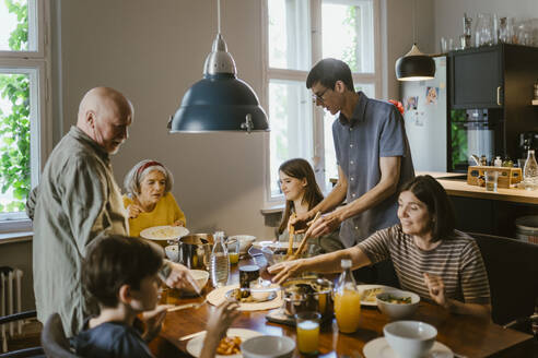 Multi-generation family having dinner at dining table in home - MASF43680