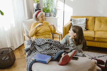 Happy senior woman spending leisure time with teenage granddaughter sitting at home - MASF43712