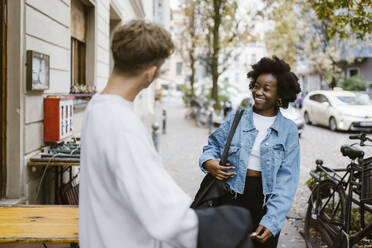 Happy woman walking while meeting boyfriend standing on sidewalk in city - MASF44002