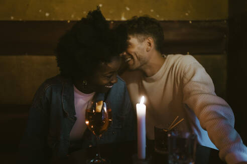 Happy multiracial couple having fun during candlelight date at bar - MASF44020