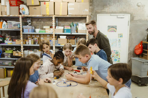 Male and female pupils working on robotics project with teacher in classroom - MASF44138