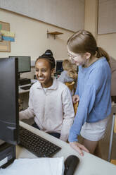 Happy multiracial girls having fun in computer class at school - MASF44206