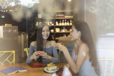 Two friends in a coffee restaurant hanging out and eating cake. - EAF00158