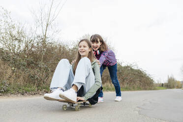 teenage girls having fun and riding each other on a skateboard - ELMF00206