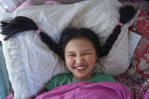USA. NY, Cute happy carefree girl with long braids relaxing on a bed - AZF00603