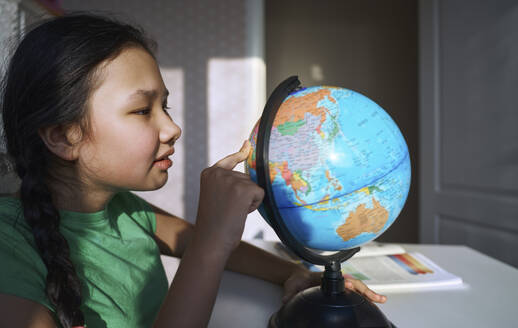 USA. NY, Cute girl at home learning geography and playing with globe - AZF00607
