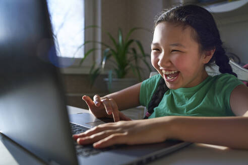 USA. NY, Cute carefree girl at home having fun with laptop - AZF00610