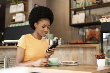 Spain, African woman having coffee, Relax - LMCF01128