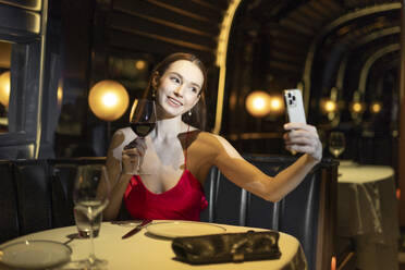 A young caucasian woman in a glamurous gown dress is having a good time at an expensive club restaurant. - EAF00171