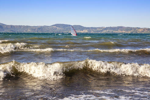Italy, Lazio, Anguillara Sabazia, Waves on Lake Bracciano with windsurfer in background - MAMF03038