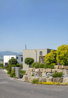 Switzerland, St Gallen Canton, Kaltbrunn, Modern suburb with stone wall in foreground - MAMF03059