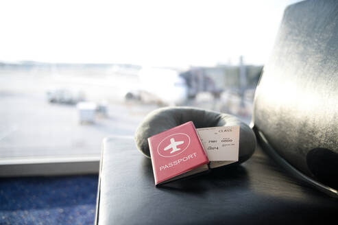 Passport and boarding pass on a lounge seat at an airport terminal with blurry background - ADSF55066