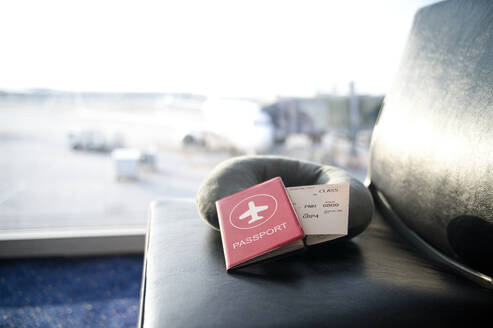 Reisepass und Bordkarte auf einem Lounge-Sitz in einem Flughafen-Terminal mit unscharfem Hintergrund - ADSF55066