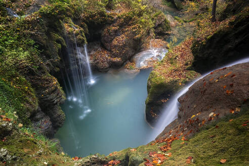 Der bezaubernde Fluss Urederra fließt durch einen herbstlich gefärbten Buchenwald in Urbasa, Navarra, und bietet einen stillen Wasserfall und ruhige smaragdgrüne Teiche - ADSF55096
