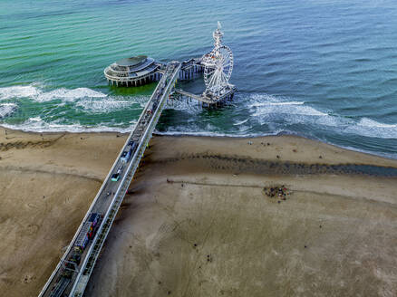 Luftaufnahme eines belebten Piers, der sich ins Meer erstreckt, mit Attraktionen und Strandbesuchern darunter. - ISF26656