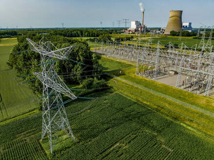 Luftaufnahme von Stromleitungen, die zu einer Industrieanlage führen, inmitten grüner Felder - ISF26662