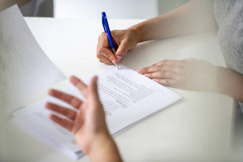 Signing important documents at a bright desk. - ISF26750