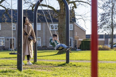 Asian mother pushing her son on the swings - ISF26829